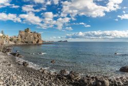 La spiaggia con ciottoli di Aci Castello e il maniero Normanno che dà il nome alla località della Sicilia