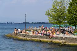 La spiaggia lungolago di Desenzano del Garda, Lombardia, con gente che prende il sole - © josefkubes / Shutterstock.com