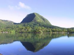 La vegetazione rigogliosa dell'isola di Huahine si rispecchia nelle acque del Pacifico del Sud, Polinesia Francese.

