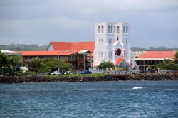 L'acqua azzurra del mare nella baia su cui si affaccia Apia, Samoa. Sullo sfondo, la facciata bianca di una chiesa cittadina.

