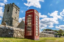 Moderno e antico sull'isola di Wight, Inghilterra: una cabina telefonica e una chiesa in pietra.

