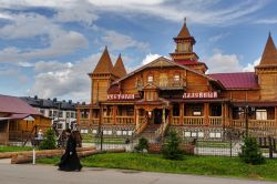 Un monaco passeggia per le vie di Tobolsk, Russia. Sullo sfondo, il ristorante Ladeyny ospitato in un edificio costruito in legno - © Sergei Butorin / Shutterstock.com