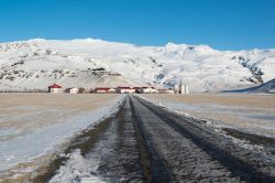 Paesaggio invernale con azienda agricola sotto il vulcano Eyjafjallajokull, Islanda. Con i suoi 78 chilometri quadrati, è il quinto ghiacciaio islandese per estensione.
