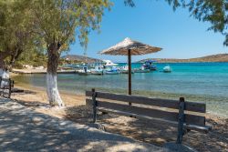 Panchine in legno e ombrellone sulla spiaggia di Blefoutis, Leros, Grecia.
