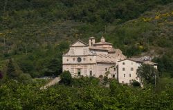 Panorama della chiesa di San Pietro a Spoleto, Umbria, immersa nella vegetazione. All'edificio religioso si accede tramite un'ampia scalinata seicentesca.
