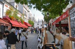 Parigi golosa: ristoranti e locali lungo una strada di Montmartre, sullo sfondo la Basilica del Sacro-Cuore - © wjarek / Shutterstock.com