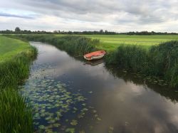 Un piccolo corso d'acqua con una barca ormeggiata sulle sponde vicino a Sneek, Frisia, Olanda.




