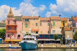 Piccolo porto di pescatori a Saint Florent, Corsica, Francia. Le abitazioni dalle facciate color pastello si rispecchiano sulle acque del porto dove sono ormeggiate le imbarcazioni su cui viaggiano ...