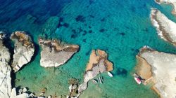 Pittoresca veduta dall'alto delle rocce vulcaniche nel villaggio di Polonia, Milos: siamo nei pressi dell'isola di Kimolos, Grecia.


