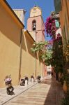 Scooters parcheggiati in un vicoletto di Saint-Tropez, Francia. Sullo sfondo, la torre campanaria di una chiesa.
