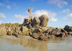 Scultura di sabbia a forma di mano su una spiaggia di Puerto Escondido, Messico.
