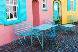 Sedie e tavolini lungo una stradina di Portmeirion, Galles, UK. Questo villaggio balneare ha un fascino e un'architettura del tutto singolari.


