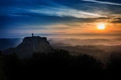 Tramonto su Civita di Bagnoregio, Viterbo. Il borgo rossiccio di Civita, su cui spicca l'esile campanile romanico della chiesa, si erge come un'isola nel mare di calanchi, creste d'argilla ...