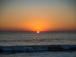 Tramonto su una spiaggia di Puerto Escondido, Messico, con le sfumature del cielo riflesse nell'acqua dell'oceano.
