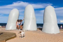 Tre ragazze in posa per una foto vicino a La Mano, Punta del Este (Uruguay): la celebre scultura è opera dell'artista Mario Irarrazabal e si trova a Playa La Brava - © RUBEN ...
