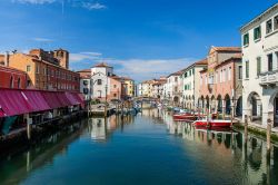 Un bel panorama del canale con barche, case e riflessi a Chioggia, Veneto, Italia. Il suo territorio si trova nella parte più a sud della provincia di Venezia e si spinge sino alle foci ...
