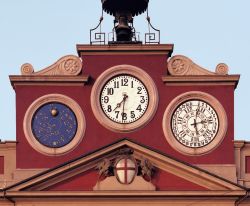 Un dettaglio della facciata del Palazzo Comunale di Alessandria, Piemonte. Noto come palazzo rosso dal colore della facciata, si presenta con un particolare orologio a tre quadranti.
