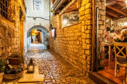 Un pittoresco vicoletto in pietra nella città di Trogir, Croazia, by night. Su un lato, uno dei tanti ristoranti tipici di questa località.

