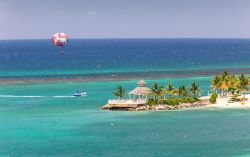Un uomo con il paracadute si diverte sopra le splendide acque del mare dei Caraibi a Ocho Rios, Giamaica.



