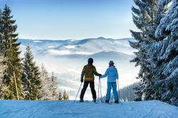 Un uomo e una donna sugli sci si tengono per mano su una pista innevata di Bukovel, Ucraina.

