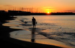 Un uomo passeggia al tramonto sulla spiaggia di Cattolica, Emilia Romagna.



