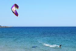 Un uomo pratica kitesurf nel tranquillo Mar Ionio a Avola, Sicilia. Questo sport acquatico nato nel 1999 consente di farsi trainare da un aquilone utilizzando il vento come propulsore - © ...