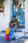 Un uomo seduto sui gradini di una casa a Inousses in Grecia - © kokixx / Shutterstock.com