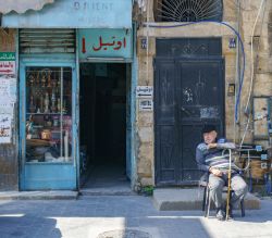 Un vecchio uomo seduto di fronte all'ingresso di un hotel a Sidone, Libano- © Catay / Shutterstock.com