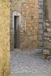 Un vicolo nel borgo storico di Pirovac, Croazia, con case in pietra e una porticina in legno.
