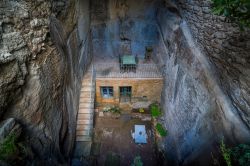 Una casa costruita nella roccia con tavolo e sedie nella terrazza a Bonnieux, Provenza, Francia.

