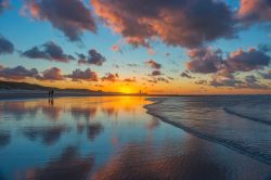 Una coppia passeggia lungo la spiaggia sabbiosa di Ostenda al tramonto, Belgio.

