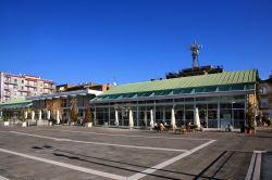 Una piazza della città di Caserta, Campania, con attività commerciali e gente a passeggio.
