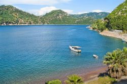 Una piccola imbarcazione bianca ancorata nel mare vicino a Marmaris, Turchia. Sullo sfondo le montagne turche fotografate in una calda giornata estiva.


