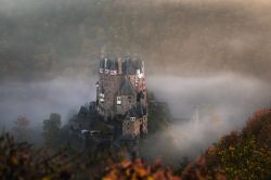 Una splendida veduta dall'alto del castello di Eltz, Wierschem, in autunno con la nebbia. Situato su una rupe rocciosa alta 70 metri, il castello è circondato sui tre lati dall'Elzbach, ...