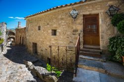 Una suggestiva casa in pietra con lanterne a forma di mulino a vento in una stradina di Bonnieux, Provenza, Francia.


