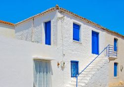 Una tradizionale casa bianca con porte e finestre blu sull'isola di Angistri, Grecia - © imagIN.gr photography / Shutterstock.com