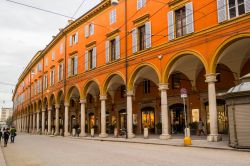 Uno scorcio del centro cittadino di Modena, Emilia-Romagna. Lo storico palazzo dalla facciata arancione è caratterizzato da un lungo porticato con negozi e attività commerciali ...