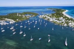 Veduta aerea del porto e del faro da Hope Town su Elbow Cay, isole di Abaco, Bahamas. Questo isolotto, popolato in origine da britannici in fuga dagli Stati Uniti d'America nel 1785, è ...