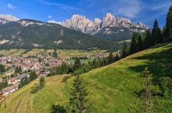 Veduta estiva della Val di Fassa con il villaggio di Pozza sullo sfondo, Trentino Alto Adige. In estate si possono effettuare passeggiate nei boschi per raccogliere bacche e funghi ma anche ...