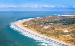 Vista aerea delle dune di sabbia e di una spiaggia con faro rosso nella provincia di Zeeland, Paesi Bassi.




