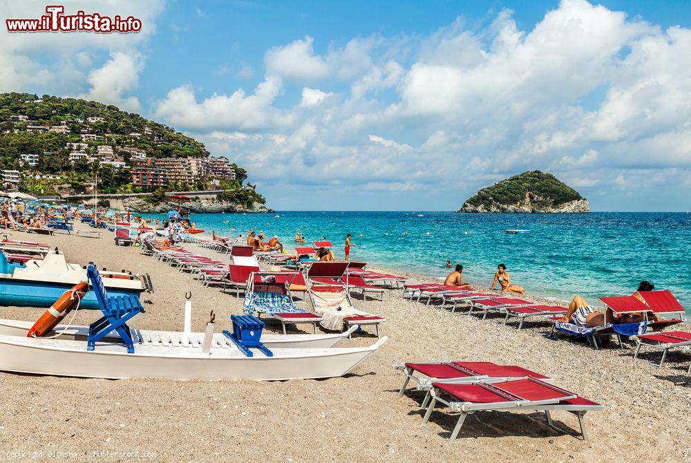 Immagine Turisti in spiaggia a Spotorno, provincia di Savona, con ombrelloni e sdraio. Sullo sfondo, l'isola di Gallinara - © Olgysha / Shutterstock.com