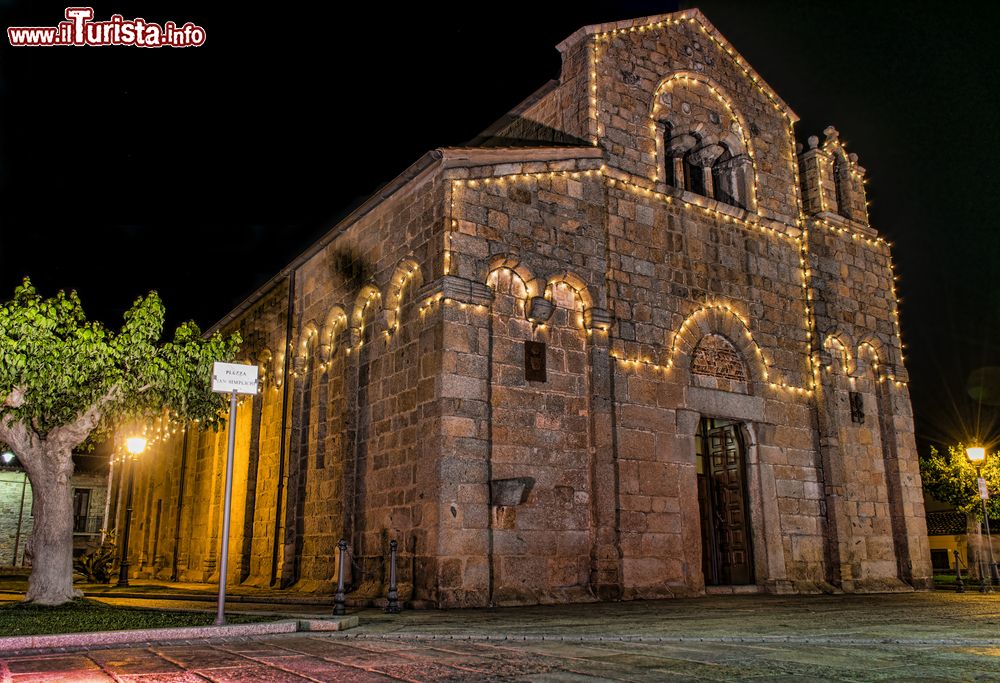 Immagine Veduta notturna della chiesa di San Simplicio a Olbia, Sardegna. L'edificio sacro presenta una facciata tripartita da due lesene e arricchita da una trifora incassata.