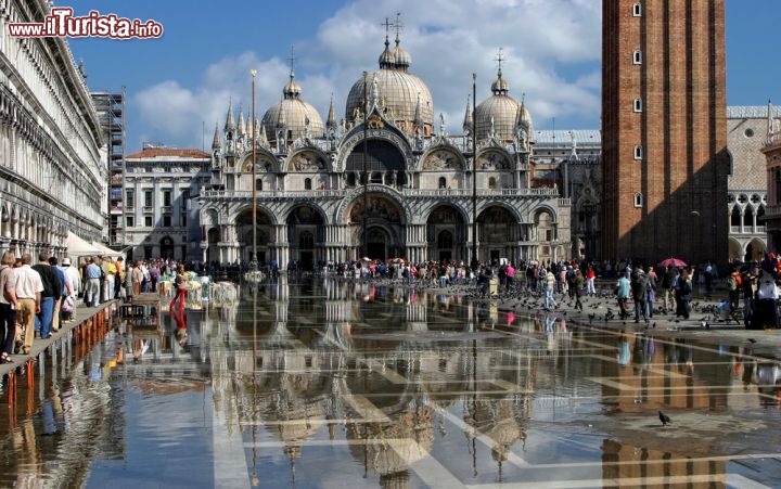 Immagine Piazza San Marco durante una fase di acqua alta a Venezia: sullo sfondo la Basilica di San Marco che si riflette sul velo d'acqua che ricopre il piazzale - © BlueMoonStore / Shutterstock.com