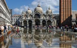 Piazza San Marco durante una fase di acqua alta a Venezia: sullo sfondo la Basilica di San Marco che si riflette sul velo d'acqua che ricopre il piazzale - © BlueMoonStore / Shutterstock.com ...