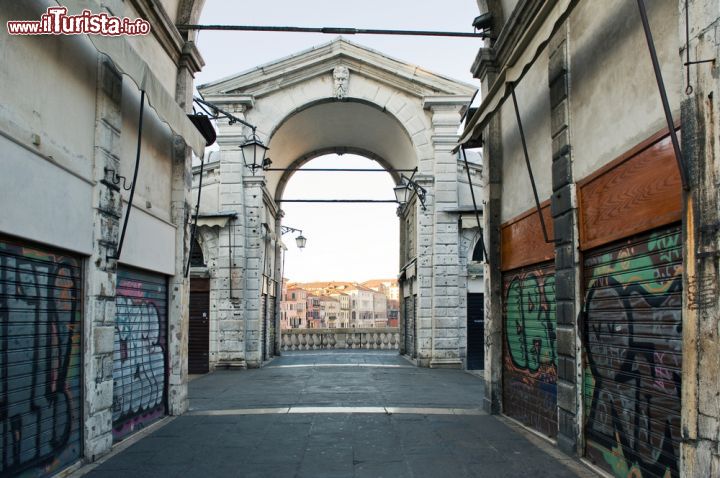 Immagine Alba a Venezia, quando la città lagunare è deserta: siamo sul Ponte di Rialto, con le vetrine dei negozi ancora chiuse, in attesa della orda di turisti che transiteranno sul ponte più antico del Canal Grande - © pio3 / Shutterstock.com