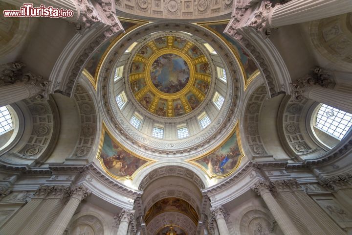 Immagine L'interno della Cappella Reale con un'immagine della cupola di Mansart dell'Hotel des Invalides, Parigi (Francia) - La volta a calotta tipica della cupola che vediamo fotografata dal basso, appare particolarmente robusta grazie ai numerosi oblò di cui è arricchita e grazie ad una struttura che appoggia il suo peso sui pilastri inferiori. Il risultato all'esterno è decisamente stucchevole ma all'interno lascia estasiati. Le linee continuamente curve e morbide danno l'illusione ottica di un'altezza ancora più sviluppata e allo stesso tempo riescono a destreggiarsi abilmente nelle volute dinamiche, dando l'idea di un fondale marino sospeso - © photogolfer / Shutterstock.com