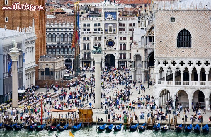 Immagine I turisti affollano Piazza e piazzetta San Marco in una giornata di sole. Si notano il Palazzo Ducale a destra, le due colonne, la base del Campanile di San Marco e la torre dell'Orologio di Venezia - © mark higgins / Shutterstock.com