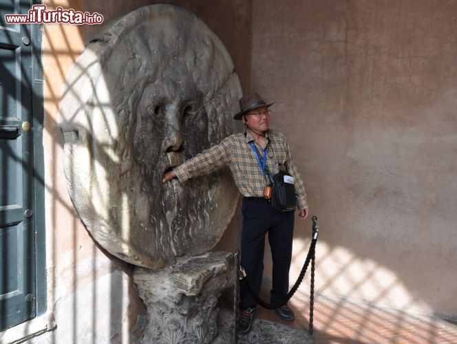 Immagine Un turista asiatico prova il mito e la leggenda della Bocca della Verità: solo chi ha la coscienza a posto supera indenne la prova! A parte gli scherzi, sono migliaia i turisti stranieri e non che si mettono in fila per farsi una foto ricordo di questo monumento, che si trova sotto al portico d'accesso della chiesa di Santa Maria in Cosmedin a Roma