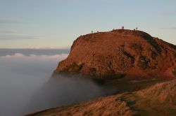 Mentre una fitta nebbia avvolge Edimburgo, la cima dell'Arthur's Peak, il vulcano spento, riesce ad emergere e ricevere gli ultimi raggi di sole - © Aga & Tomek Adameczek / ...