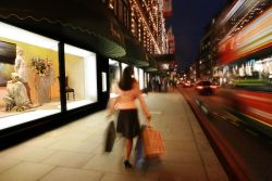 Una donna intenta nello shopping cammina davanti alle vetrine di Harrods, a Londra - © visitlondonimages / britainonview / Juliet White